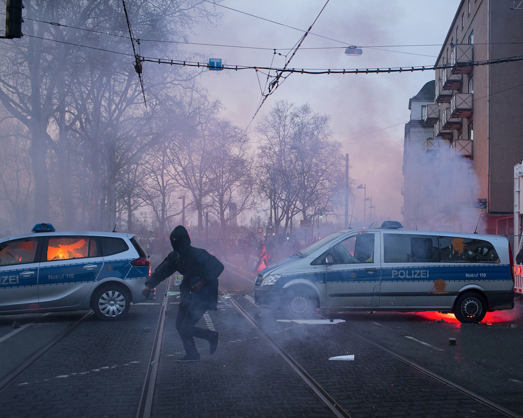 Violent protesters attack police cars and burn the left one on the picture about 500m from the new headquarters of the European Central Bank.