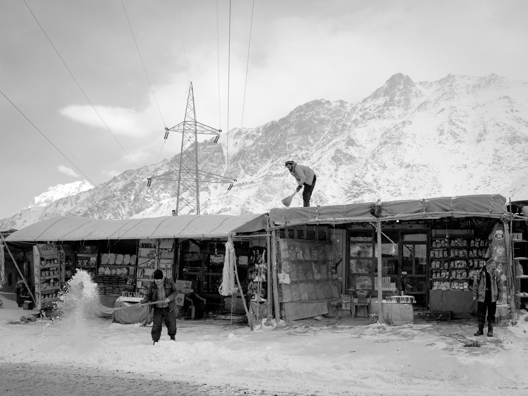 Shop keepers at the northern end of the Salang tunnel clean their shop fronts and roofs from the fresh snow fallen over night.