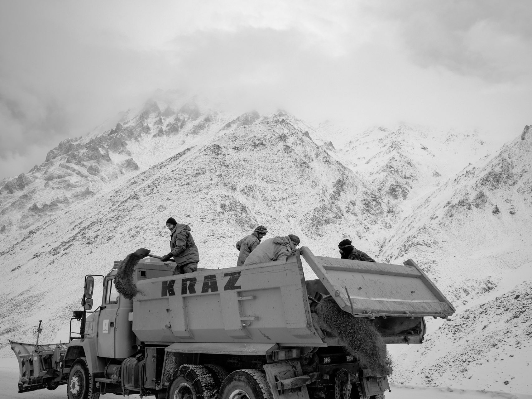 Workers of the Salang tunnel directorate sprinkle sand on the iced surface of the road.