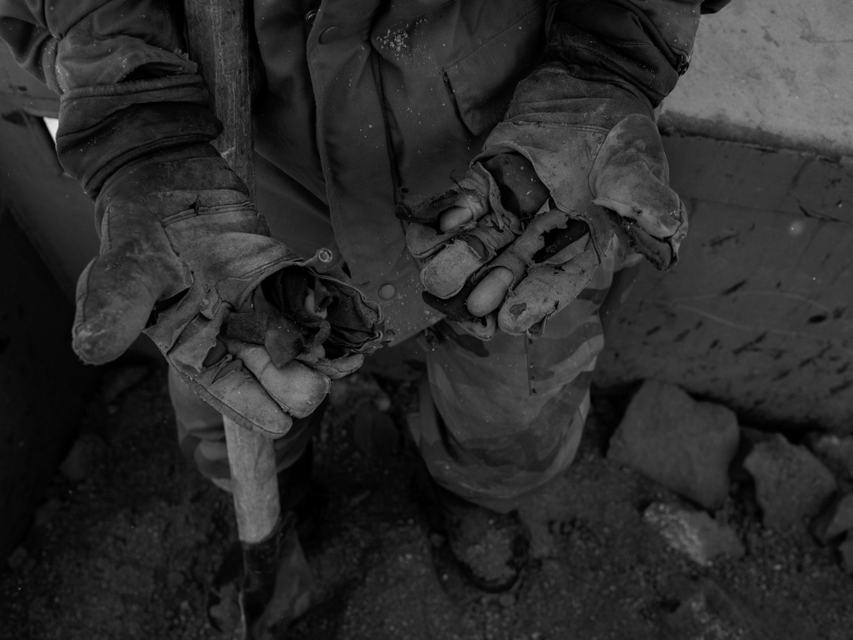 A service worker of the Salang tunnel shows his worn out working gloves prior to start sprinkling sand on the iced surface of the road.